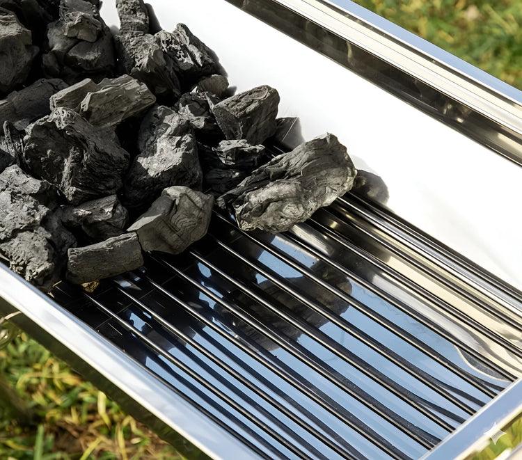 Close-up of charcoal briquettes inside the fire box of a stainless steel portable BBQ grill 1066