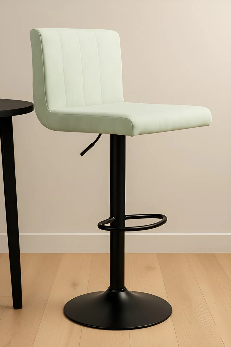 Light green bar stool with black base on a wooden floor.