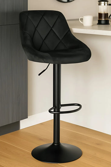 Black velvet bar stool in a kitchen setting with a counter and coffee maker.