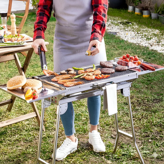 A person grilling shrimp and burger patties on a large stainless steel charcoal BBQ grill 1066